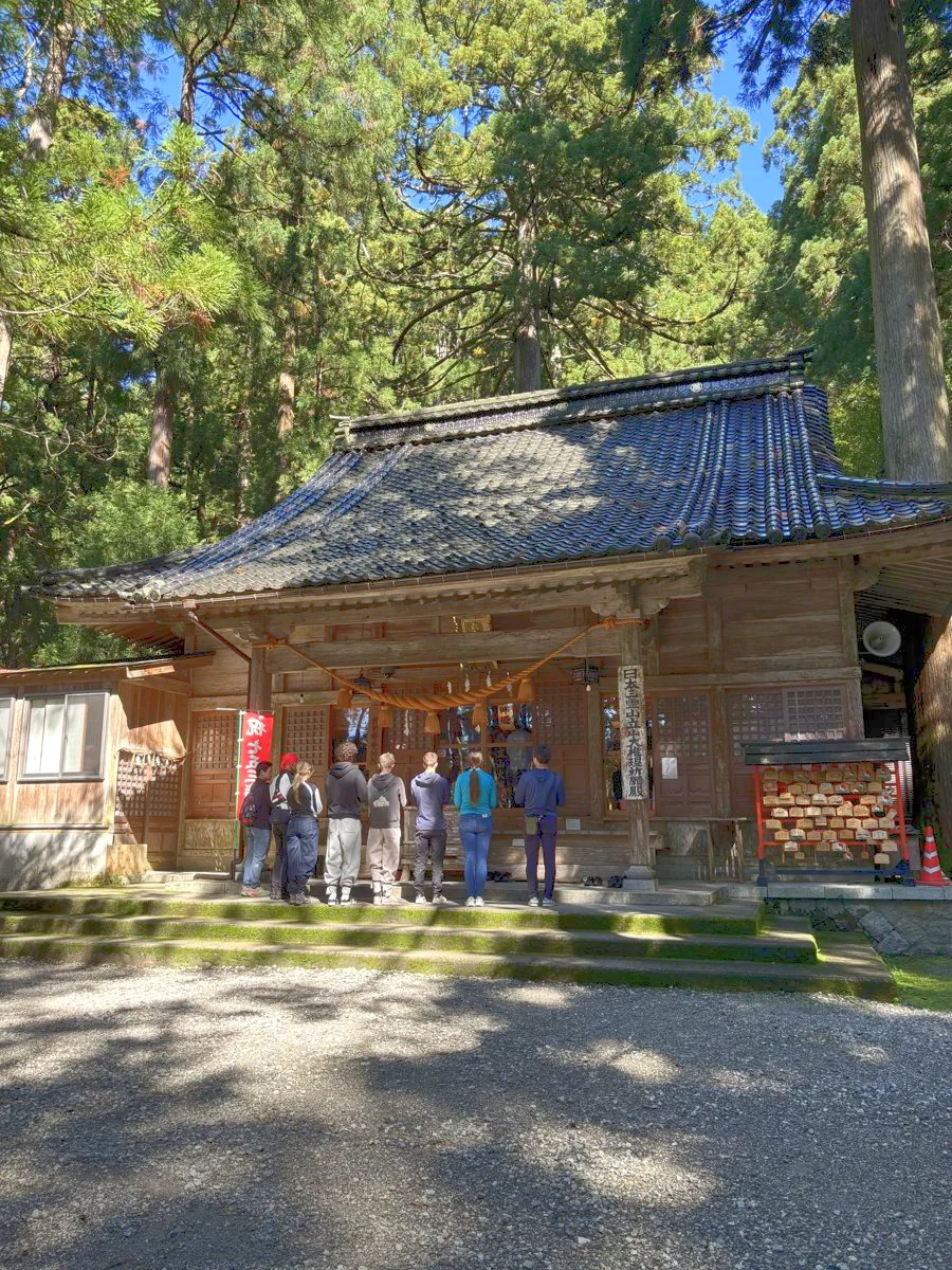 杉の大木に囲まれた雄山神社中宮祈願殿の前に並ぶ参加者