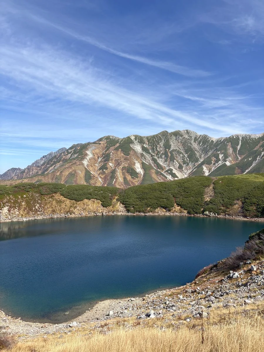 青い水をたたえたみくりが池と、その向こうに連なる山並み