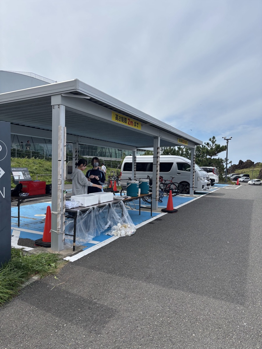 屋根の下にテーブルを並べた屋外のエイド