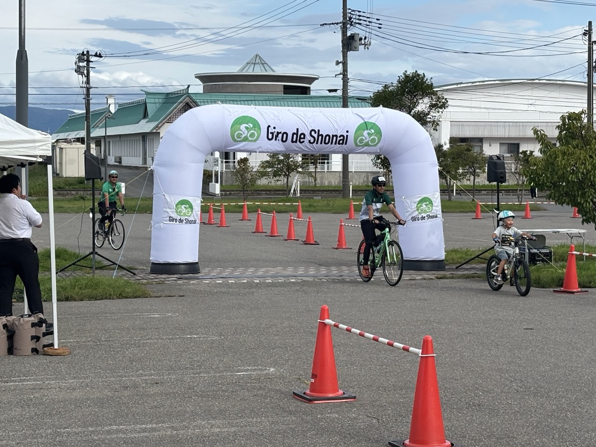 コーンで区切られた道を通って、Giro de Shonaiのゲートへゴールする参加者