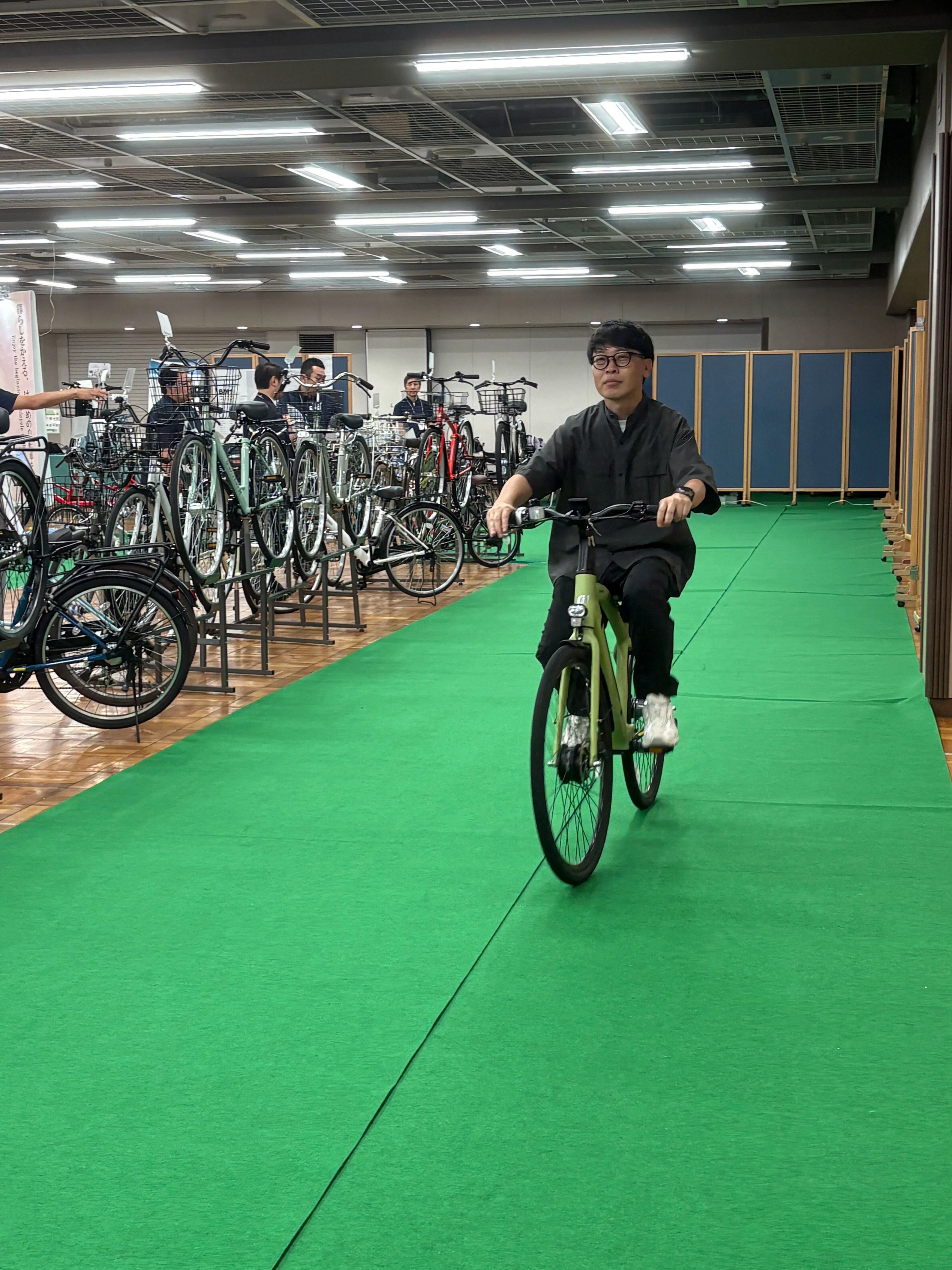 丸石サイクルのシャフトドライブ電動アシスト自転車を会場で試乗する様子